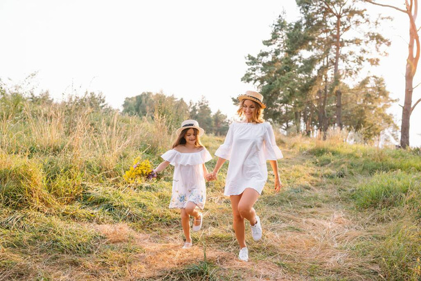 Anya és lánya jól érzik magukat a parkban. Boldogság és harmónia a családi életben. Szépség természet jelenet családi szabadtéri életmód. - Fotó, kép