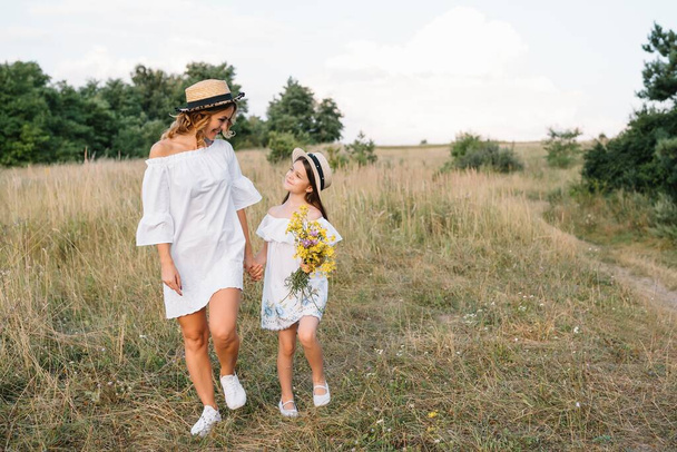 Stylish mother and handsome daughter having fun on the nature. Happy family concept. Beauty nature scene with family outdoor lifestyle. family resting together. Happiness in family life. Mothers day - Foto, afbeelding