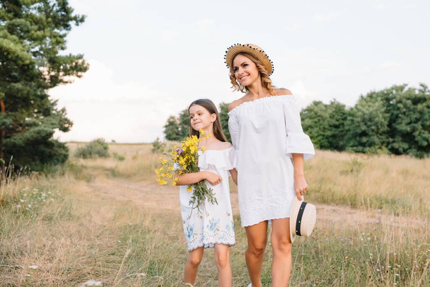 Stylish mother and handsome daughter having fun on the nature. Happy family concept. Beauty nature scene with family outdoor lifestyle. family resting together. Happiness in family life. Mothers day - Zdjęcie, obraz