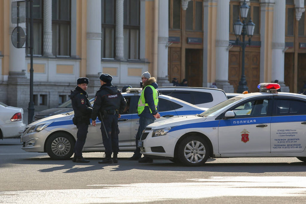 Saint-petersburg, Russia - 7 April 2020: : Nevsky Prospekt, Vosstaniya Square. Side view of a police car and several officers in uniform standing and talking by road - Foto, afbeelding
