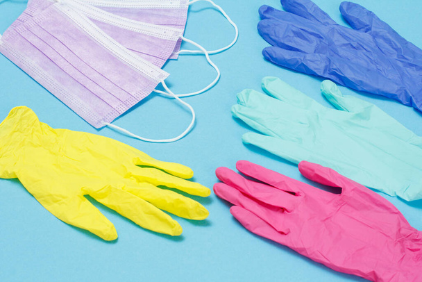 Verschillende kleuren latex handschoenen en medische maskers voor persoonlijke bescherming. Bovenaanzicht. Concept van de coronavirusbeschermingsuitrusting. - Foto, afbeelding
