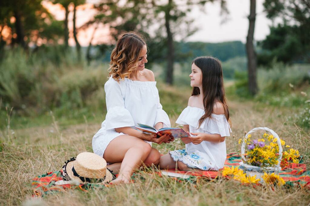 Stylish mother and handsome daughter having fun on the nature. Happy family concept. Beauty nature scene with family outdoor lifestyle. family resting together. Happiness in family life. Mothers day - Фото, изображение
