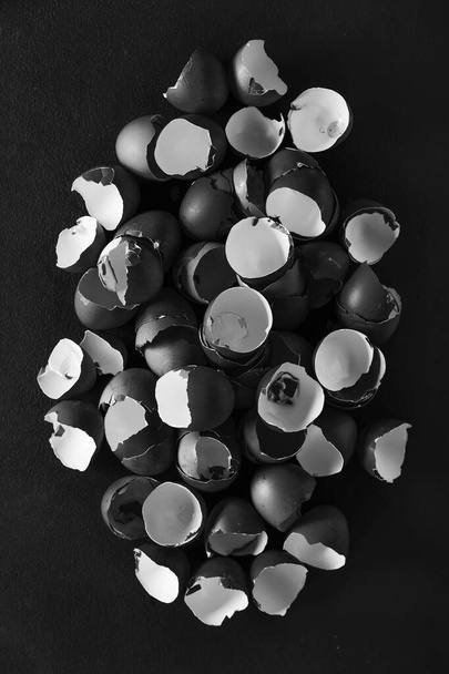 Photo en noir et blanc. Concept Pâques et Carême. Un tas de fragments de coquilles d'oeuf sur fond noir. - Photo, image