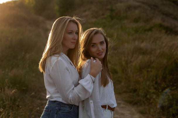 deux belles sœurs adultes en chemisiers blancs se dressent sur un sentier herbeux à la campagne
 - Photo, image