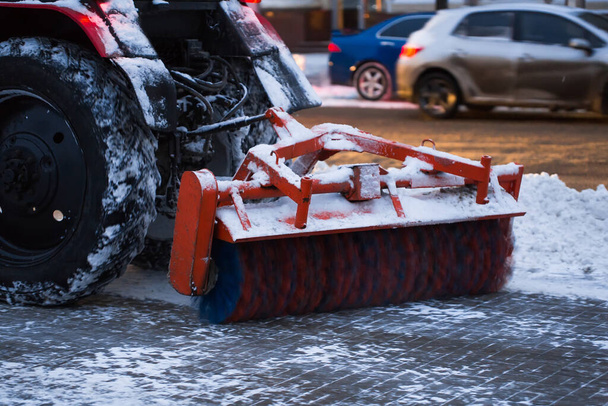 Τρακτέρ καθαρίζει το χιόνι με μια βούρτσα στη λεωφόρο της πόλης. - Φωτογραφία, εικόνα