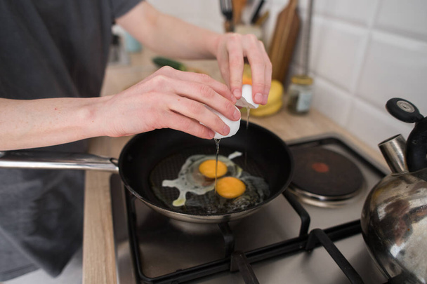 young girl prepares eggs in light kitchen, scandinavian style - Foto, Imagen