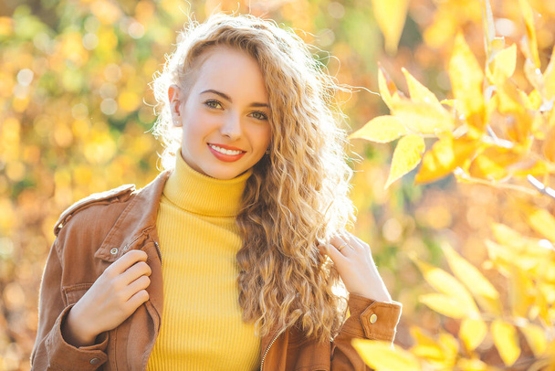 Close up portrait of beautiful blond girl on autumn background. Stylish young lady in park. Beautiful blond girl outdoors. - Zdjęcie, obraz