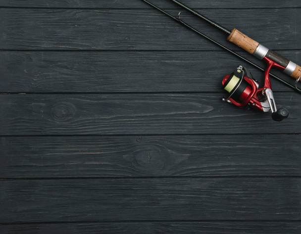 Fishing tackle - fishing spinning, hooks and lures on darken wooden background. Top view. - Фото, изображение