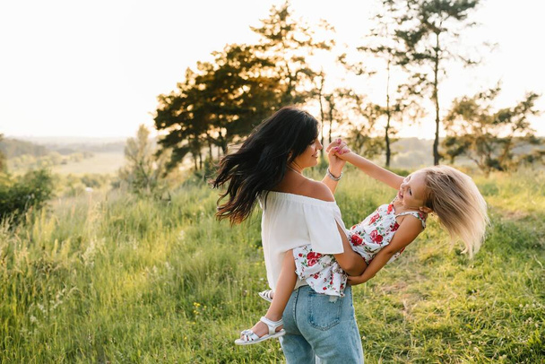 Mother and daughter having fun in the park. Happiness and harmony in family life. Beauty nature scene with family outdoor lifestyle. - Фото, изображение