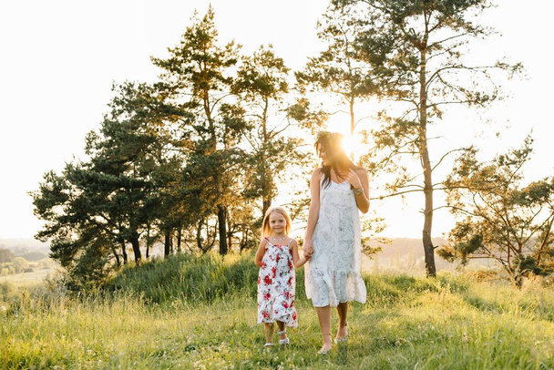 Mother and daughter having fun in the park. Happiness and harmony in family life. Beauty nature scene with family outdoor lifestyle. - Foto, Imagem