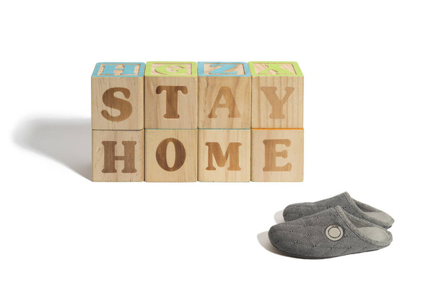 Stay home. message written on wood blocks with house slippers to emphasize concept on white background - Photo, Image