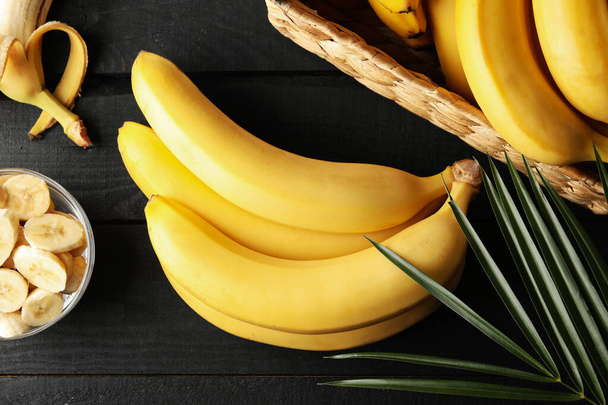 Bananas. Cesta com bananas e tigela com fatias em fundo de madeira
 - Foto, Imagem