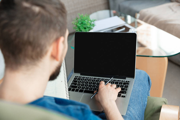 Mladý soustředěný muž studující doma během on-line kurzů nebo informace zdarma sám - Fotografie, Obrázek