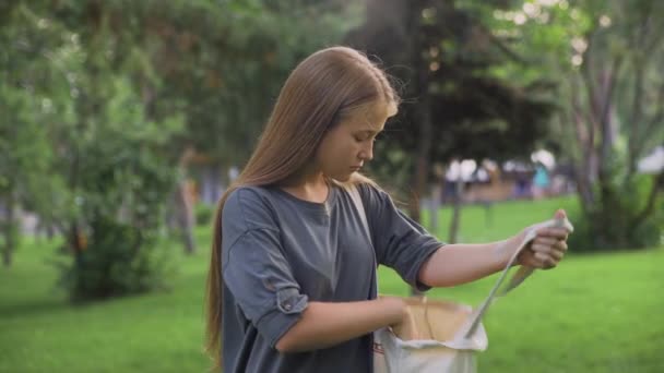 Young girl drinking orange juice outdoors at summer park - Materiał filmowy, wideo