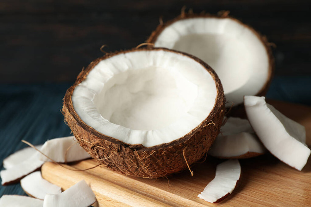 Board with coconut on wooden background, close up - Photo, Image