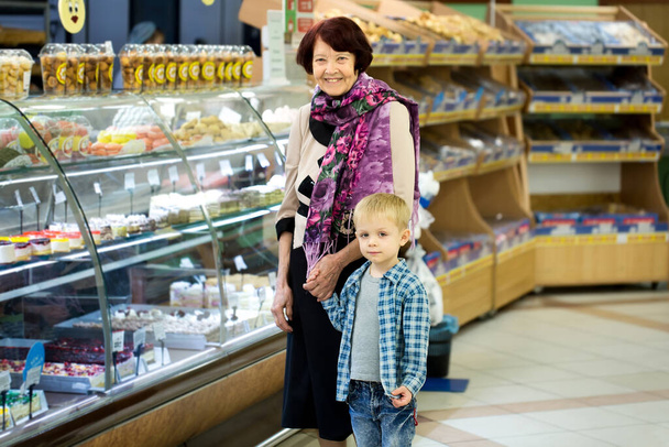 Adult woman with child choosing dessert while shopping in supermarket. - Zdjęcie, obraz