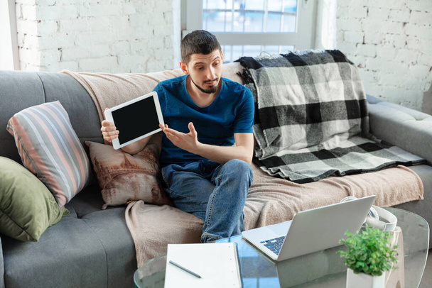 Молодий зосереджений чоловік навчається вдома під час онлайн-курсів або безкоштовної інформації за допомогою шипіння
 - Фото, зображення