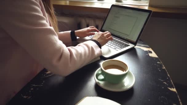 İş kadını serbest olarak bilgisayar dizüstü bilgisayarı ve cep telefonu üzerinde çalışıyor, kahve dükkanındaki sehpanın üzerinde kahve fincanı var. Kafe barında kahve molası sırasında dizüstü bilgisayarda çalışan üniversiteli kız. - Video, Çekim