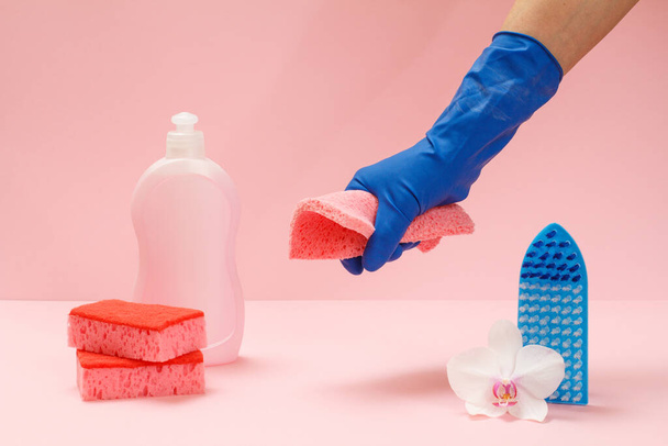 Plastic bottle of dishwashing liquid, sponges, brush and a hand in a rubber glove holding a rag on the pink background. Washing and cleaning set. - Fotoğraf, Görsel