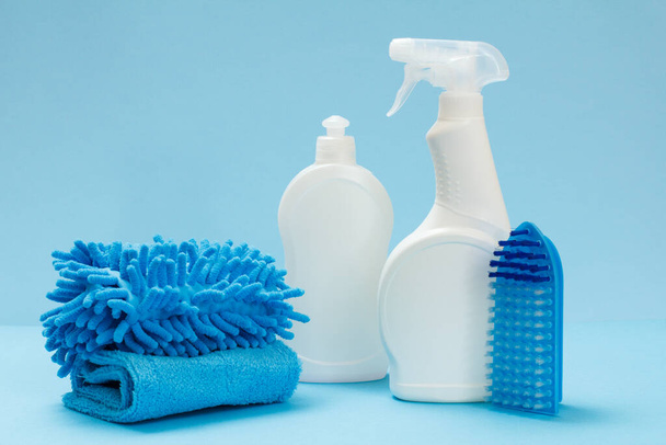 Bouteilles en plastique de liquide vaisselle, nettoyant pour vitres et carreaux, chiffons et brosse sur fond bleu. Set de lavage et de nettoyage
. - Photo, image
