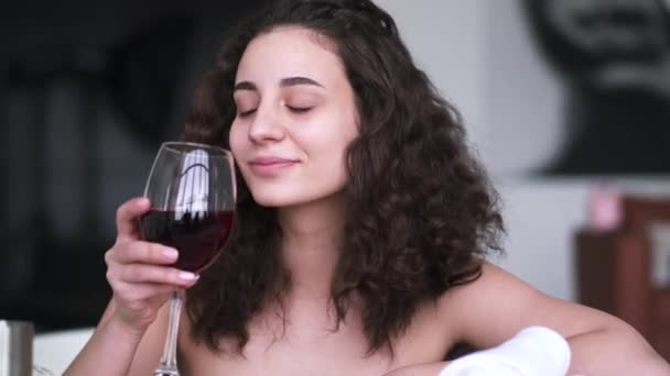 Portrait of brown-eyed brunette woman drinking wine in bath. Young beautiful Caucasian girl enjoying alcohol as resting in bathroom at home or in hotel. - Filmmaterial, Video