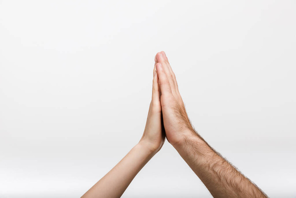 Closeup image of a man's and woman's hands give a high five to each other isolated over white wall background. - Photo, Image