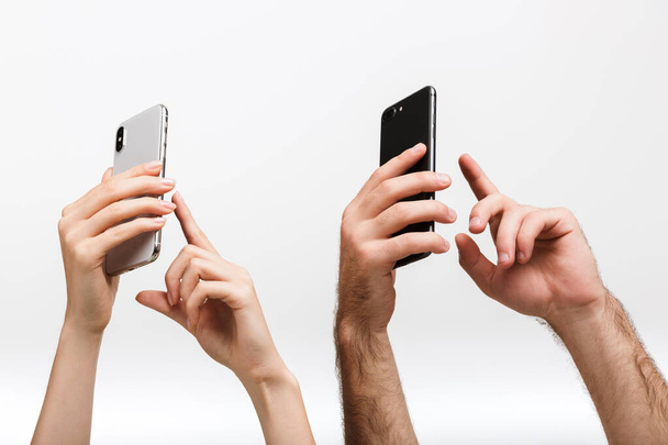 Closeup photo of a man's and woman's hands isolated over white wall background holding mobile phones take a photo. - Φωτογραφία, εικόνα