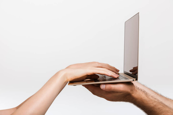 Closeup image of a man's and woman's hands isolated over white wall background holding laptop computer typing. - Zdjęcie, obraz
