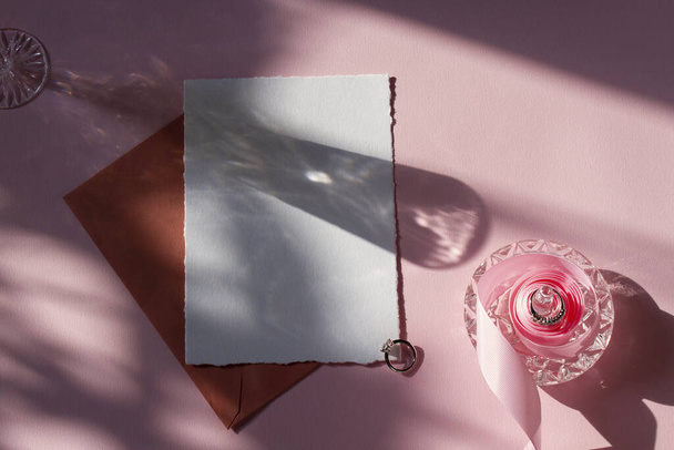 Κάρτα mockup με ροζ κορδέλα, φάκελο, σκιές σε ροζ φόντο. Για προσκλήσεις γάμου, χαιρετισμούς, γενέθλια. - Φωτογραφία, εικόνα