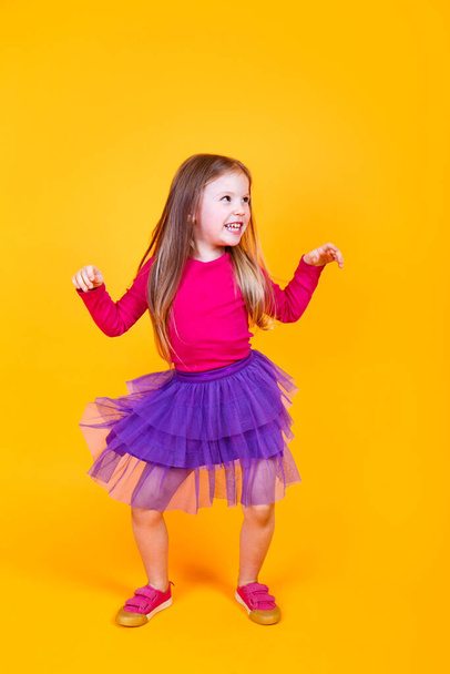 Little cute child kid baby girl 4-5 years old wearing light clothes dancing on yellow studio background - 写真・画像
