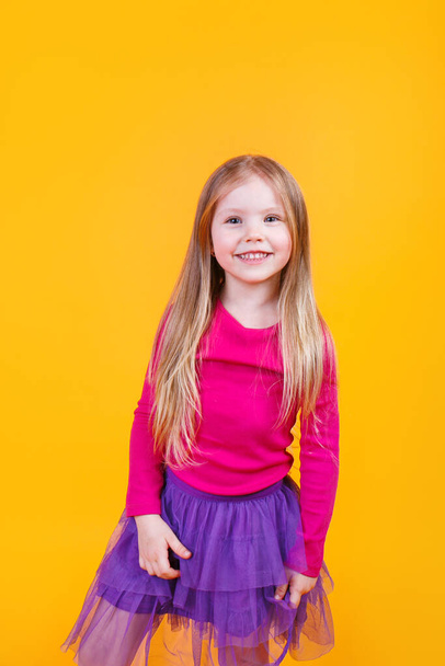 Portrait of adorable little girl 5-6 years with beautiful long hair on yellow studio background - Fotografie, Obrázek