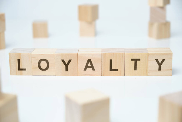 Modern business buzzword - loyalty. Word on wooden blocks on a white background. Close up. - 写真・画像