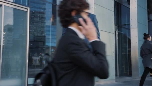 Uomo d'affari caucasico in giacca e cravatta sta utilizzando uno smartphone su una strada nel centro della città. Altre persone dell'ufficio camminano oltre. E 'sicuro di se' e sembra avere successo. Sta navigando sul web sul suo dispositivo.
. - Filmati, video