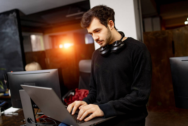 Software-Entwickler sitzt mit Laptop in der Hand am Schreibtisch. Modernes Büro bei Entwicklungsgesellschaft - Foto, Bild