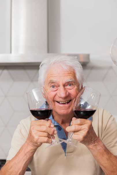 Portrait, homme âgé joyeux tenant deux verres à vin rouge
 - Photo, image