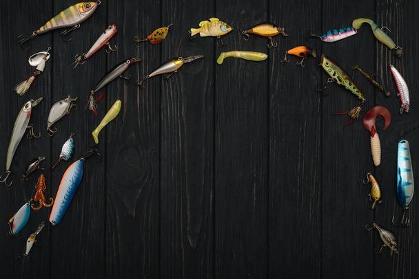 Fishing tackle - fishing spinning, hooks and lures on darken wooden background. Top view. - Fotó, kép