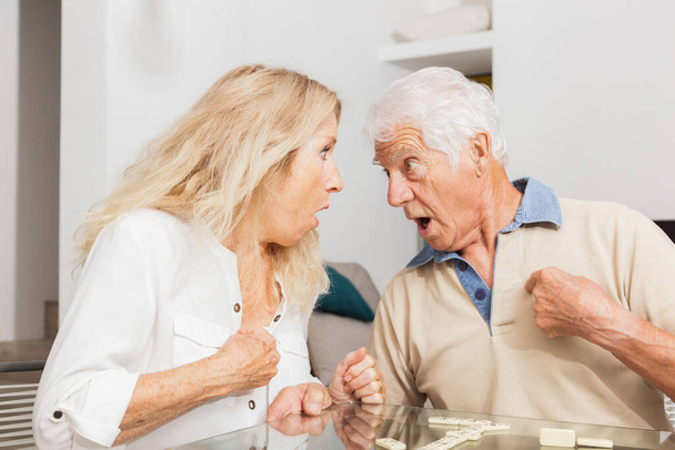 Senior-Paar in vollem Streit. Streit. Frau und Mann beim Dominospiel - Foto, Bild