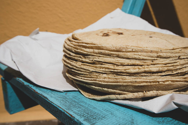 Stack of Corn Tortillas on Paper and Blue Wood - Фото, изображение