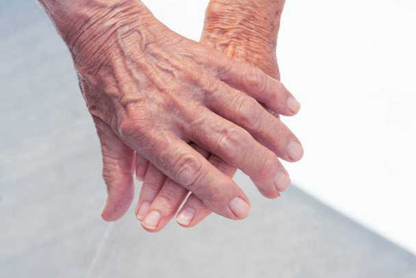 Старший мужчина держит старшую женщину за руки, крупным планом. Нежный жест
. - Фото, изображение