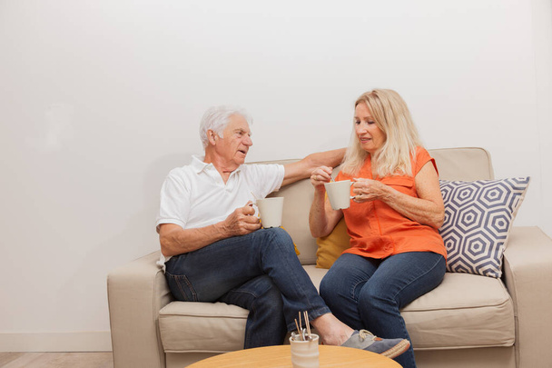 Felice coppia anziana bere un tè, seduto sul divano in soggiorno
 - Foto, immagini