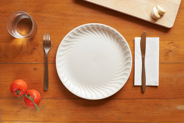 Porcelain plate and cutlery against a wood background with mediterranean elements - Foto, immagini