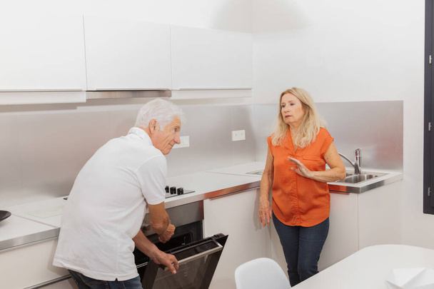 Casal sênior conversando em uma cozinha
 - Foto, Imagem