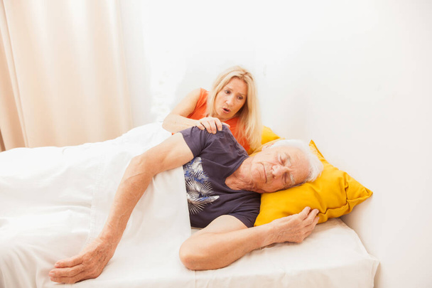Старшая пара в постели. Мужчина спит и видит сны. Женщина проснулась в спальне
 - Фото, изображение