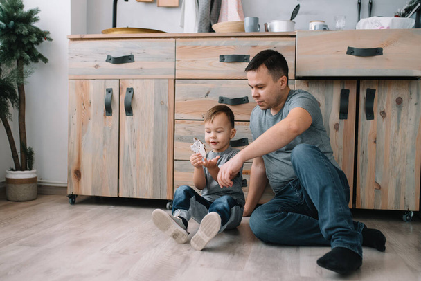 Young man and his son with oven sheet in kitchen. Father with little son on the kitchen - Valokuva, kuva