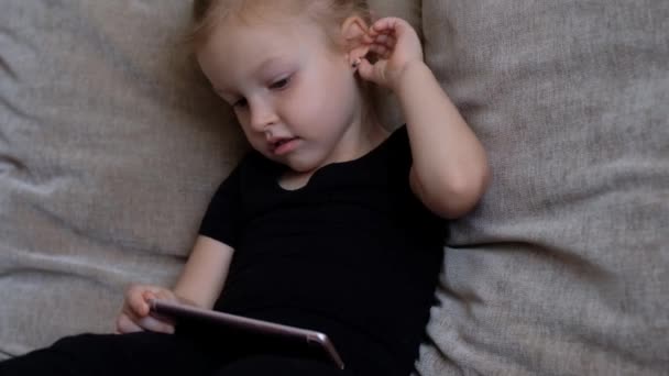 Distance learning, online education for kids. Little girl studying at home in front of the smartphone. Child watching online cartoons, kids computer addiction, parental control. Quarantine at home - Кадри, відео