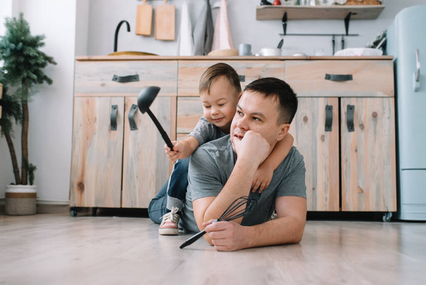 Νεαρός και ο γιος του με λαμαρίνα στην κουζίνα. Πατέρας με μικρό γιο στην κουζίνα. - Φωτογραφία, εικόνα