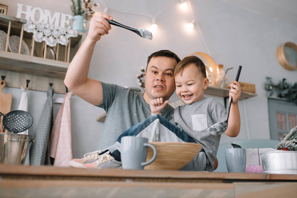 Young man and his son with oven sheet in kitchen. Father with little son on the kitchen - Photo, image