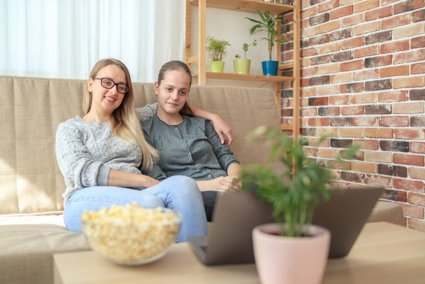 Mother with daughter sitting on sofa and watching series - Foto, imagen
