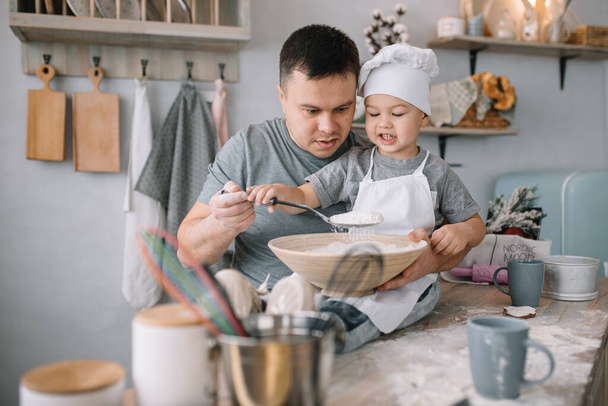 Young man and his son with oven sheet in kitchen. Father with little son on the kitchen - Фото, зображення