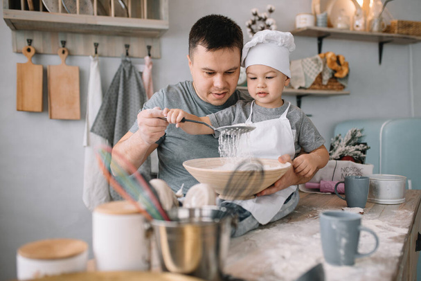 Young man and his son with oven sheet in kitchen. Father with little son on the kitchen - Фото, зображення